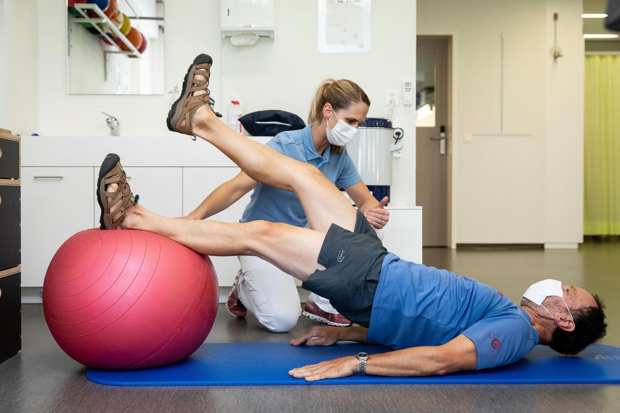 Therapist directs patient who is lying on the floor and exercising the hip.