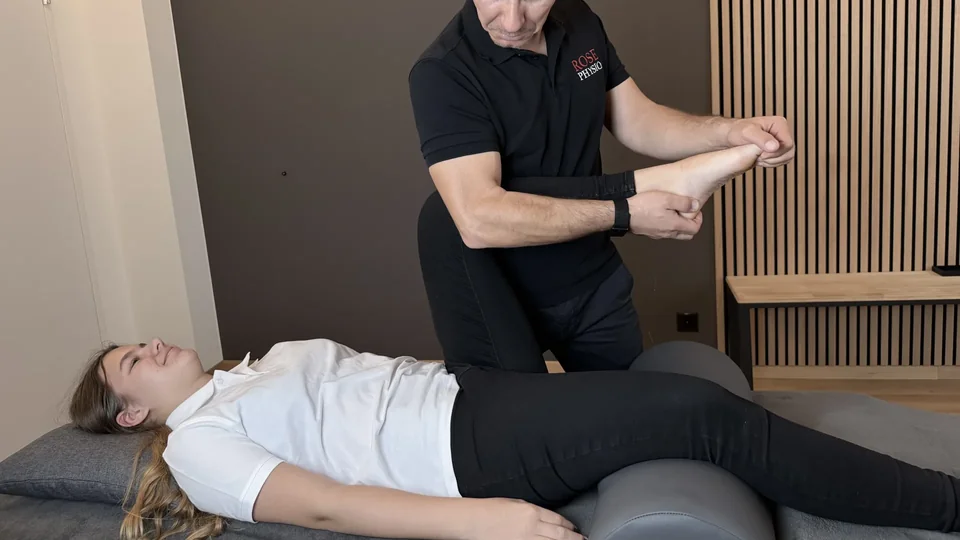 Physiotherapeut mobilisiert den Fuss einer Patientin auf einer Behandlungsliege