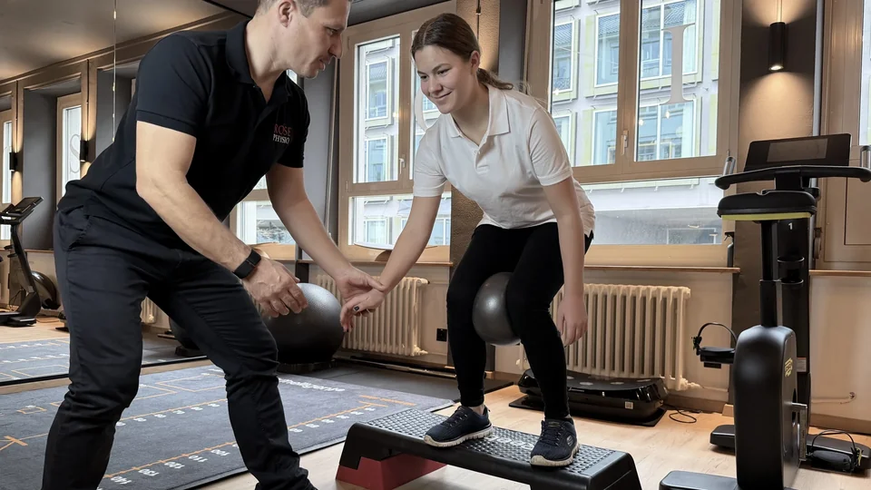 Physiotherapeut begleitet eine Patientin bei einer Übung auf einer Trainingsplattform